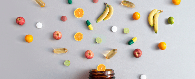 brown mason jar with various fresh ingredients floating above it